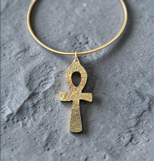 Gold ankh pendant on a textured gray background