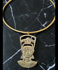 Gold necklace with a pendant of a face on a black marble surface